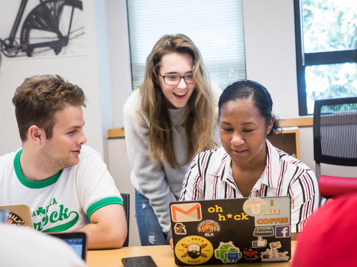 A small group of students looking at a laptop