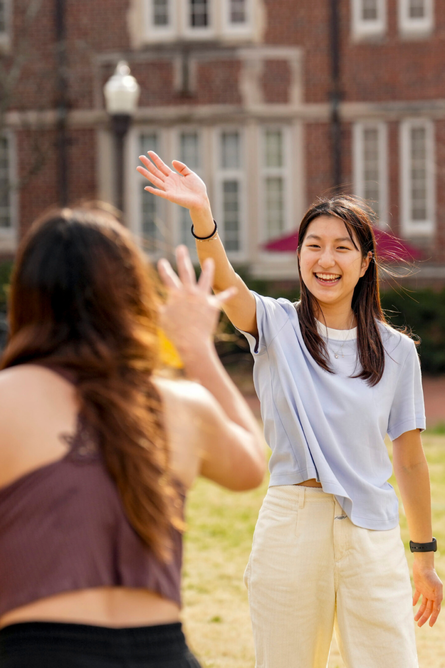 Students wave to each other on campus